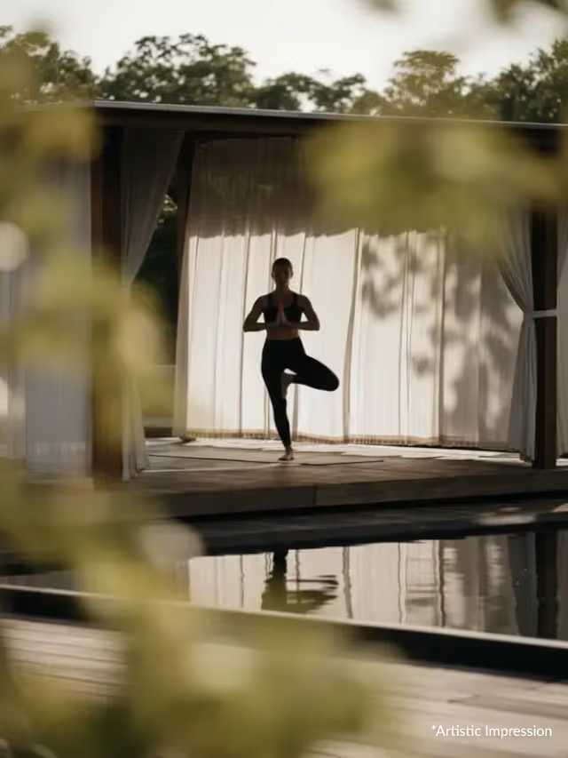 Person practising yoga in an open pavilion beside a reflecting pool